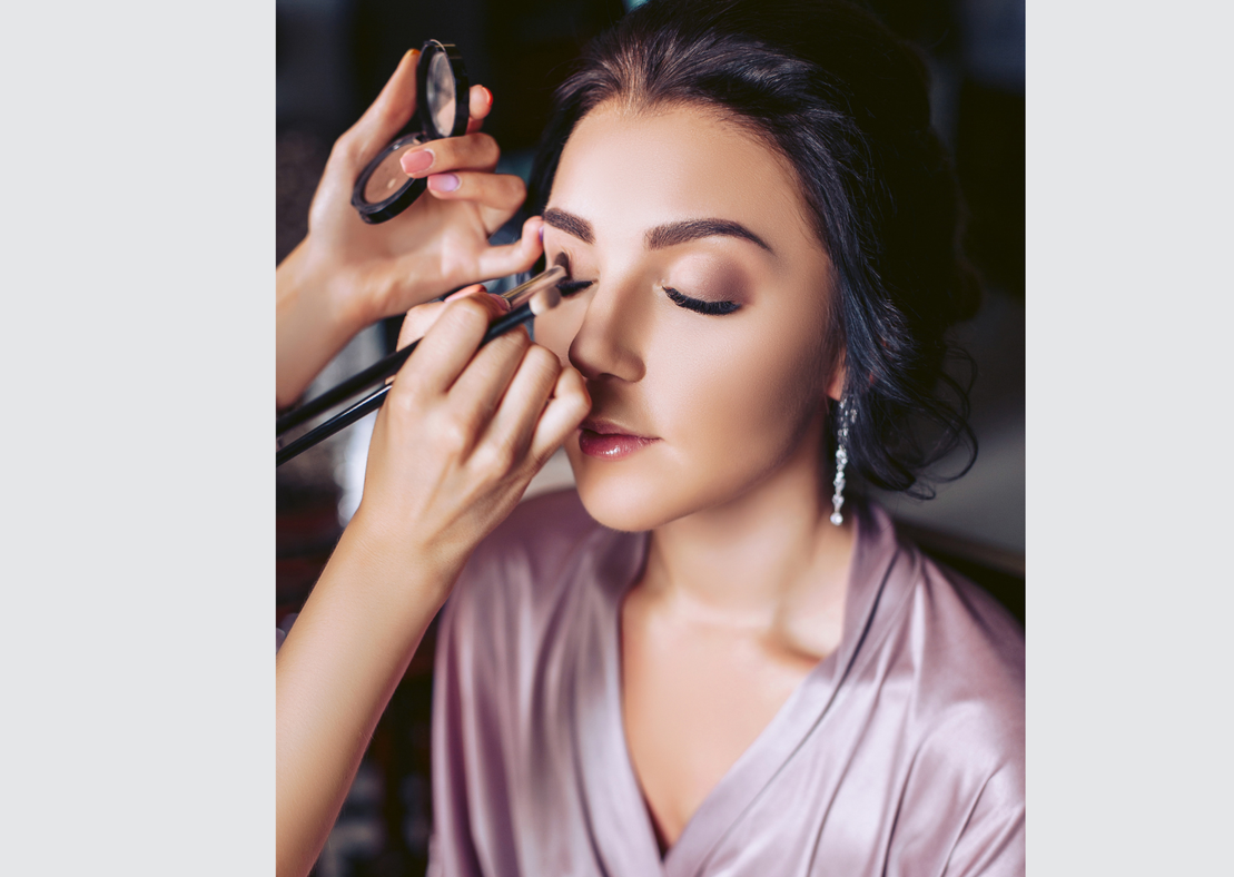 Beraterin, die einer Kundin beim Make-up im Spiegel hilft